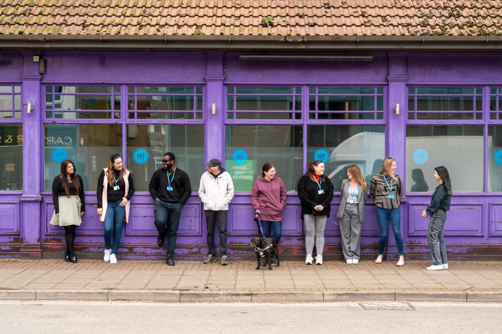 York Road Project members and dog standing outside of a purple building