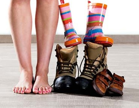 Woman standing with men's shoes and children's wellies